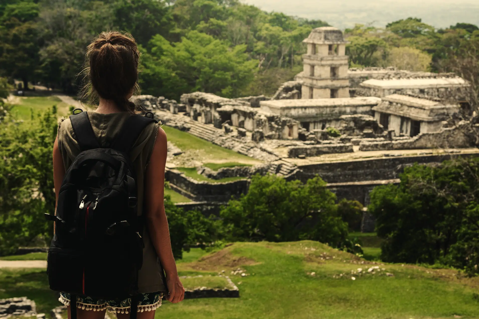 A traveller with a backpack standing beside a Maya ruin